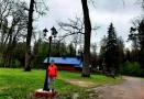chłopczyk stojący przy ozdobnej lampie zewnątrzej, w tle cerkiewka z niebieskim dachem na Krynoczce