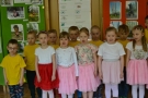 Dzieci z grupy czwartej stoją przed publicznością i śpiewają piosenkę.