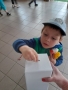 dzieci na tle plakatu UNICEFU, każde z nich wrzuca do puszki pieniądze. 