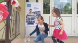 dzieci na tle plakatu UNICEFU, każde z nich wrzuca do puszki pieniądze. 