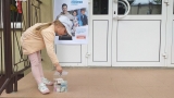 dzieci na tle plakatu UNICEFU, każde z nich wrzuca do puszki pieniądze. 