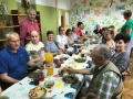 grupa uczestników siedząca przy stole, na którym stoi poczęstunek 