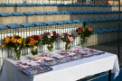 stół, na którym stoi pięć bukietów kwiatów i leżą medale oraz dyplomy