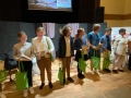 Siedem osób stoi na scenie, trzymają zielone torby