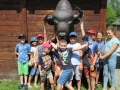 Grupa dzieci pozuje do zdjęcia. Nad głowami widać posąg głowy żubra.