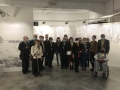 grupa ludzi pozuje do zdjęcia. W tle widać wystawę
