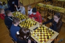 Młodzież grająca w szachy przy kilku stołach