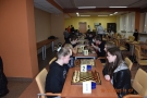 Dzieci siedzą przy stole naprzeciw siebie i grają w szachy.