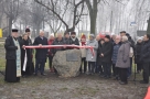 Zdjęcie grupowe, uczestnicy uroczystości stoją po obu stronach kamienia z tablicą, trzymając biało - czerwoną wstęgę