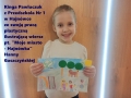 Uśmiechnięta dziewczynka trzyma pracę plastyczną