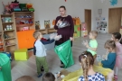 Pani trzyma worek na śmieci, dzieci uczą się segregacji odpadów.