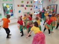 Dzieci w kolorowych strojach tańczą.