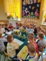Dzieci siedzą przy stole i czytają książki.