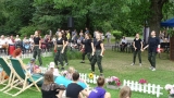 Pokaz taneczny, grupa tancerek ubrana w jednakowe ciemne stroje.