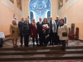 zdecie grupowe artystów i włodarzy miasta oraz powiatu, na tle ołtarza w kościele