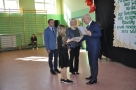 burmistrz wręcza akt nadania sytpendium dziewczynce. Obok stoją również rodzice dziecka. Wszyscy ubrani na galowo. 