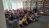 Zdjęcie grupowe, na którym siedzą na podłodze i na krzesłach uczniowe hajnowskich szkół.