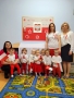 Zdjęcie grupowe dzieci i opiekunek, w tle Godło Polski.