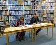 kobieta i mężczyzna usadzeni za stołem podpisują dokumenty