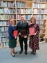 dwie koniety i mężczyzna na tle regałów z książkami