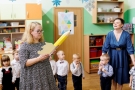 Pani dyrektor trzyma w dłoniach duzy żółty ołówej obok dzieci i opiekunka.