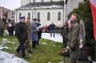 meżczyźni w mundurzach składają przy pomniku wiązankę. Z prawej strony stoi żołnierz na warcie.