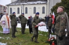 Młodzież z klasy wojskowej w mundurach składaa przy pomniku wiązankę. Z prawej strony stoi żołnierz na warcie.