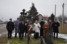 delegacje samorządowe i duchowni w Orzeszkowie. W tle widać zabudowania i krzyż.