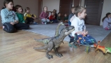 dzieci oglądają bajkę, obok ustawione są zabawki - dinozaury