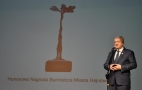mężczyzna przy mikrowonie W tle widać wyświetlaną grafikę przedstawiającą Querkus