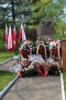 obelisk 3 Maja ze złożonymi kwiatami i stojącymi przy nim flagami Polski