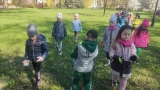 Dzieci zaopatrzone w rękawiczki i worki sprzątają teren parku.