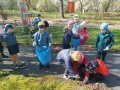 dzieci  w niebieskich rękawiczkach sprzątają śmieci do worków