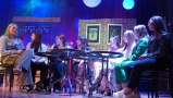 Dziewczęta siedzą przy stolikach. Sceneria jak w kawiarni.