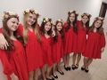 Dziewczynki w czerwonych sukienkach mają na głowach wianki.