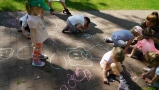 Dzieci rysują kredą po chodniku