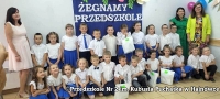 zdjęcie grupowe przedszkolaków wraz z opiekunami na tle niebieskiego baneru z napisem Żegnamy przedszkole