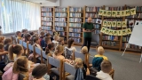 dzieci przybyłe do biblioteki na urodziny, przed nimi stoi autor przygód o żubrze Pompiku Tomasz Samojlik