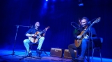 Dwaj mężczyśni grający  na gitarach. 