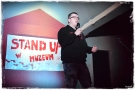 mężczyzna z mikrofonem. W tle widać podświetlony napis STAND UP 