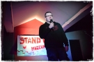 mężczyzna z mikrofonem. W tle widać podświetlony napis STAND UP 