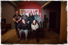 grupa ludzi. W tle widać podświetlony napis STAND UP 