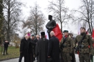 zaproszone osobistości osłaniaja pomnik. Obok żołnierze pełnią wartę. 