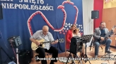 dwaj panowie grają na gitarach, kobieta trzyma na kolanach dziecko