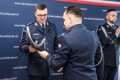 mężczyzna przekazuje drugiemu mężczyźnie dokumenty. Obaj są w mundurach