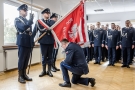 mężczyzna w mundurze klęka przed sztandarem