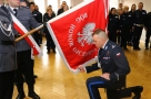 mężczyzna w mundurze klęka przy sztandarze z napisem: "Bóg Honor Ojczyzna"