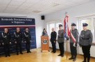 przymównicy stoi kobieta, z prawej strony poczet sztandarowy, z lewej mężczyźni w mundurach