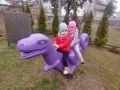 dzieci bujają się na fioletowym dinozaurze