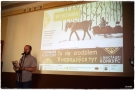dyrektor przemawia do mikrofonu. W tle widać plakat promujacy konkurs wyświetlany na rzutniku ekranu